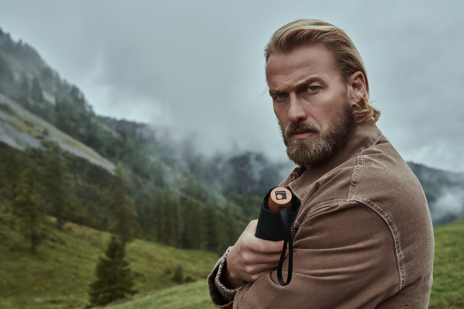 Mann hält geschlossenen Taschenschirm in seiner Hand